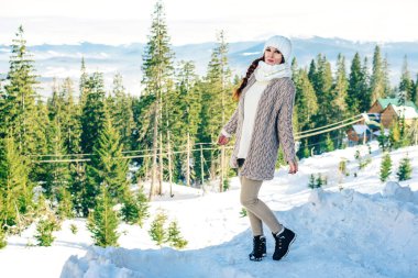 Kışın arkasında karlı bir dağ olan kızıl saçlı kız.