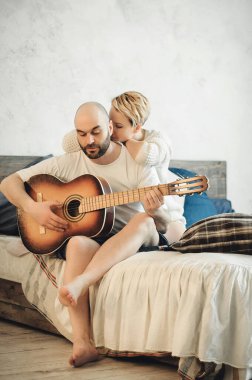 Sakallı bir adam ve sarışın bir kız yatakta oturuyor. Gitar, kitap, şampanya, duygular, aşk. Aşk hikayesi..