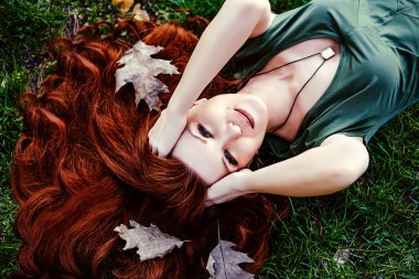 Sonbaharda ya da bahar parkında gülümseyen kızıl saçlı kız.