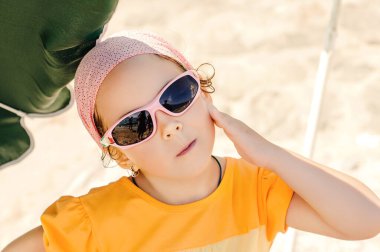 Güneş gözlüklü mutlu küçük kız güneşe bakıyor.