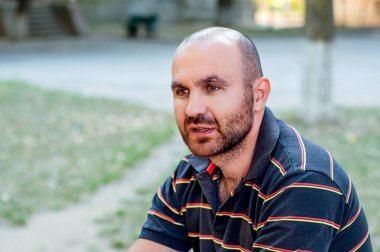 Genç bir adam parkta bir bankta oturur ve röportaj verir.