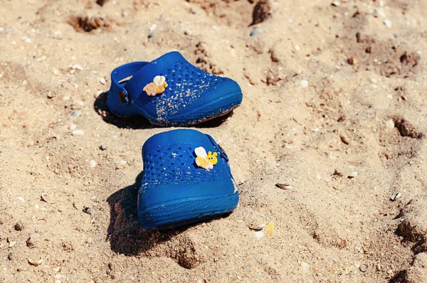 Children\'s blue rubber shoes on the beach.