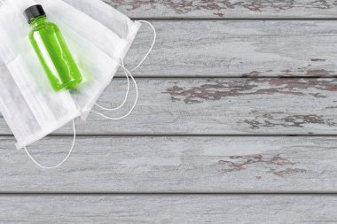 Coronavirus salgını koruması. Evde kal. Virüs koruma ürünleri, tek kullanımlık antiviral maske ve antiseptik, gri ahşap arka planda. COVID-19