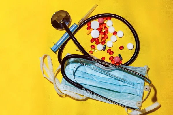Protective mask, medicines, thermometer, stethoscope and syringe with coronavirus text on a yellow background. Novel coronavirus 2019-nCoV, MERS-Cov middle East respiratory syndrome coronavirus.