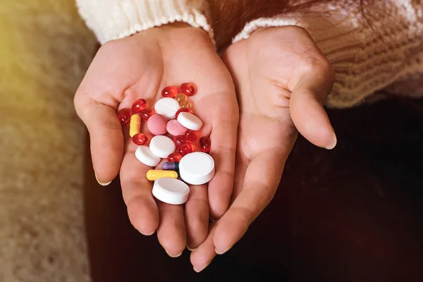 Yeşil arka planda bir kadının elindeki haplar. Bağışıklığı arttırmak ve koronavirüsü önlemek için vitamin ve tıbbi kompleks.