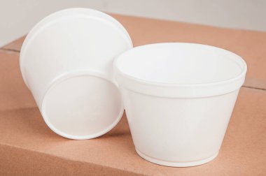 Kapalı beyaz fincanlar izole edilmiş bir arka planda karton bir kutunun üzerinde duruyor..