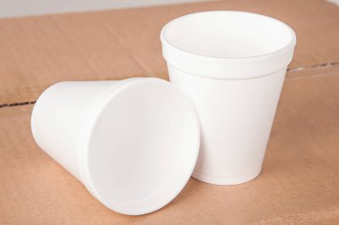 Kapalı beyaz fincanlar izole edilmiş bir arka planda karton bir kutunun üzerinde duruyor..