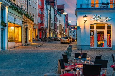 Münih, Almanya - SEPTEMBER 28, 2014: Münih, Bavyera, Almanya, Avrupa 'daki eski şehir caddesi. Gün batımı sahnesi ön planda kafe masaları ve arka planda bulutlu gökyüzü