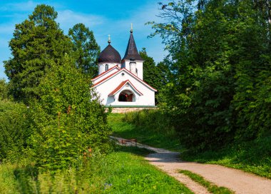 Yazın Beyaz Rusya Kilisesi. Arka planda bulutlu gökyüzü ve önplanda yol.
