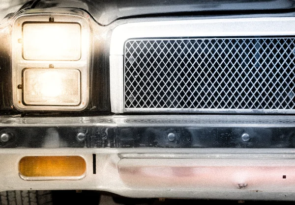 Détail du phare éclairé et de la grille de voiture — Photo