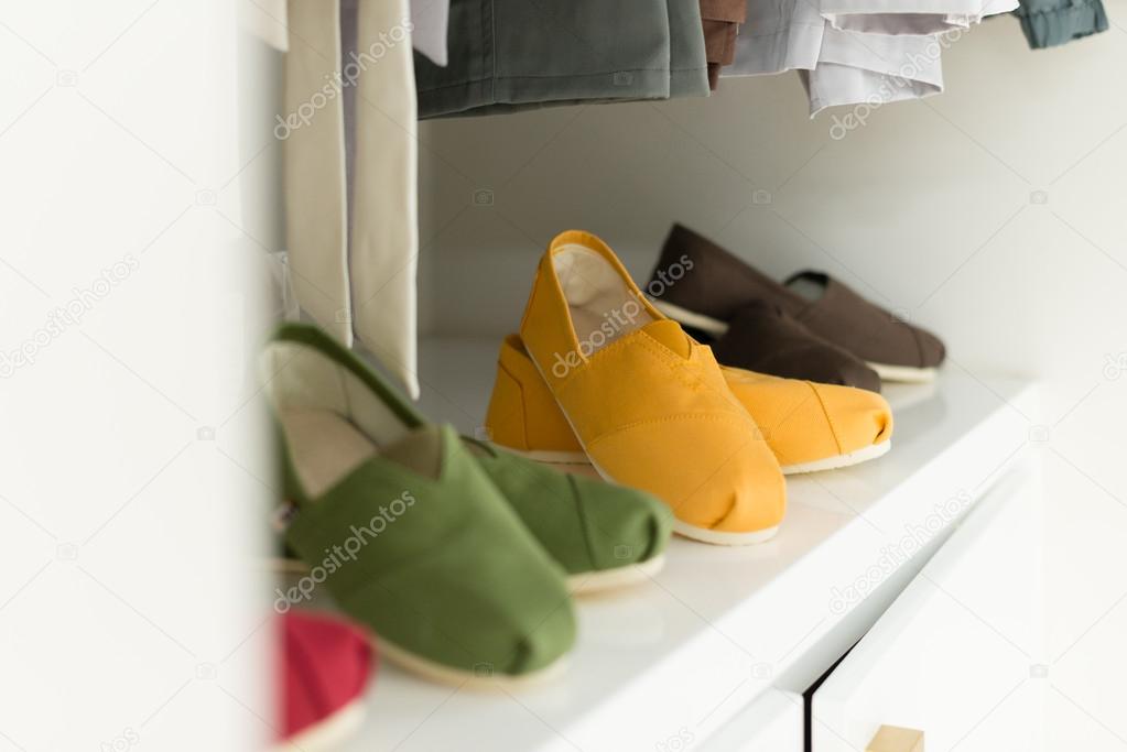 Casual clothes on hangers and shoes at shop.