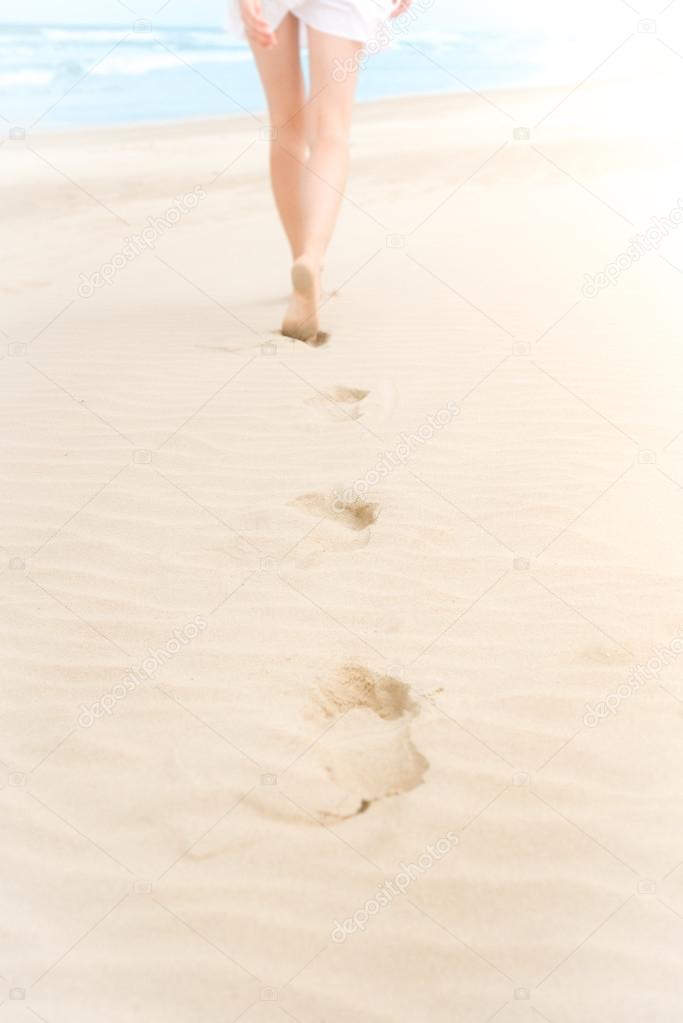 Slim girl in white swimsuit walking to ocean.