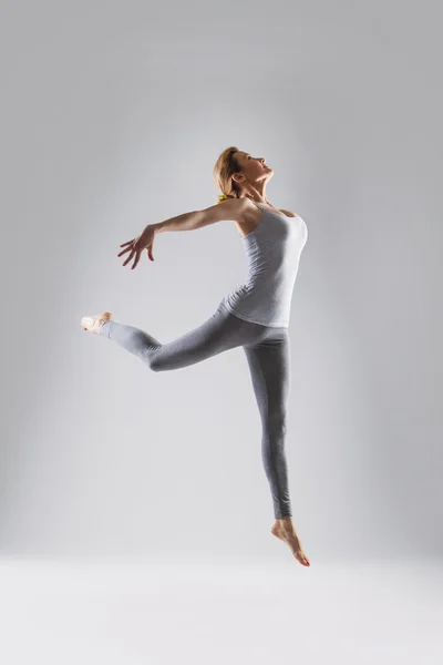 Vacker ung kvinna gör yoga på en grå studio bakgrund — Stockfoto