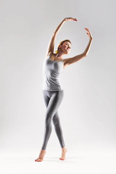 Vacker ung kvinna gör yoga på en grå studio bakgrund — Stockfoto