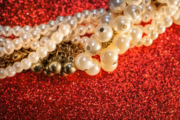 Close up de pérolas brancas em um fundo de brilho vermelho . — Fotografia de Stock