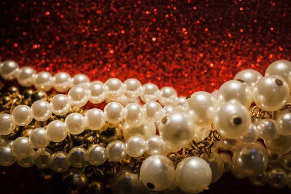 Närbild på vita pärlor på en röd glitter bakgrund. — Stockfoto