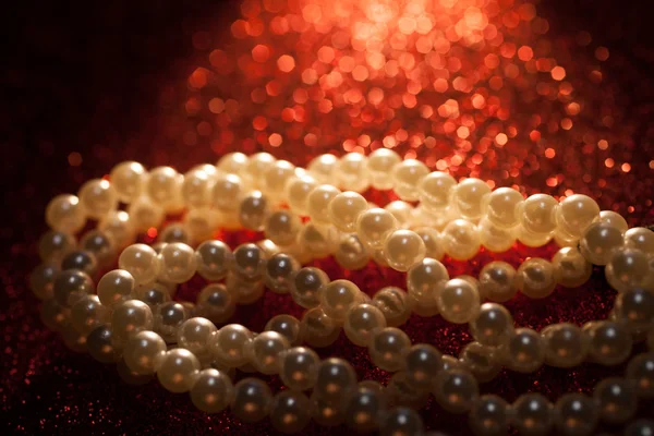 赤いキラキラ背景上の白い真珠のクローズ アップ. — ストック写真