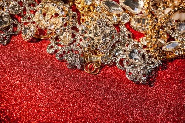 赤い光沢のあるキラキラ背景に黄金と銀のジュエリー — ストック写真