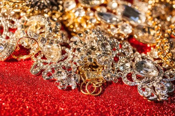 Gouden en zilveren sieraden op rood glanzend glitter achtergrond — Stockfoto