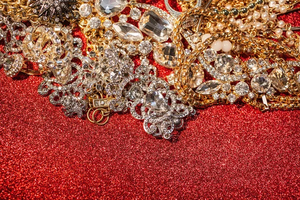 Gold- und Silberschmuck auf rot glänzendem Glitzerhintergrund — Stockfoto