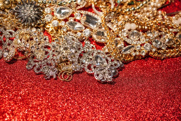 Gold- und Silberschmuck auf rot glänzendem Glitzerhintergrund — Stockfoto