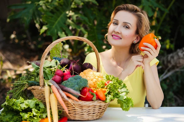 Mulher sorridente com cesta cheia de legumes ao ar livre. Estilo de vida saudável . — Fotografia de Stock