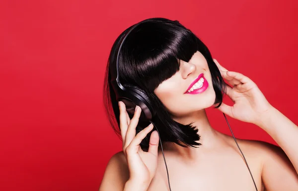 Kobieta, słuchanie muzyki na słuchawkach ciesząc się taniec. Zbliżenie portret pięknej dziewczyny z różowe usta i czarną perukę — Zdjęcie stockowe