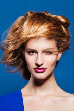 Portrait of lovely young model with beautiful hairstyle. on blue background clipart