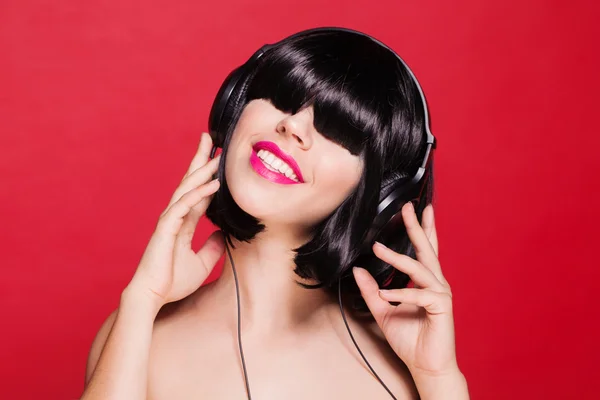 Joven hermosa mujer DJ disfrutando de la música en los auriculares. sobre fondo rojo — Foto de Stock