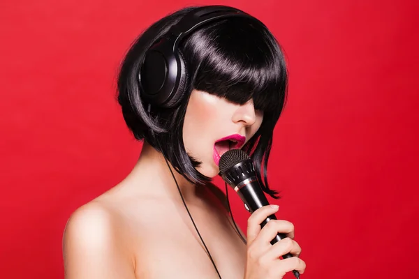 Mikrofon ile güzel şarkı söyleyen kadın. Şarkıcı. Karaoke şarkı. kırmızı zemin üzerine