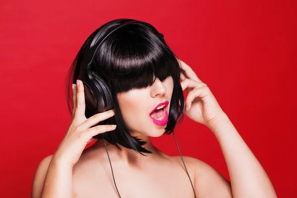 Woman listening to music on headphones enjoying a dance. Closeup portrait of beautiful girl with pink lips — ストック写真