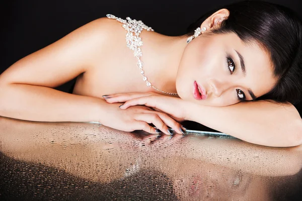 Schöne sexy brünette asiatische Modell mit Luxus-Accessoires und ihr Spiegelbild in Spiegeltisch — Stockfoto