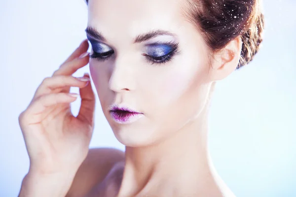 Close up retrato de mulher com olhos fumegantes sobre fundo de inverno azul. Mulher de beleza de inverno. Rainha da neve. Maquilhagem — Fotografia de Stock