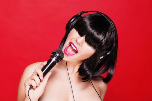 Karaoke kadın bir şarkı zevk kulaklıklar müzik dinlemek. Pembe dudakları ile güzel kız closeup portresi.