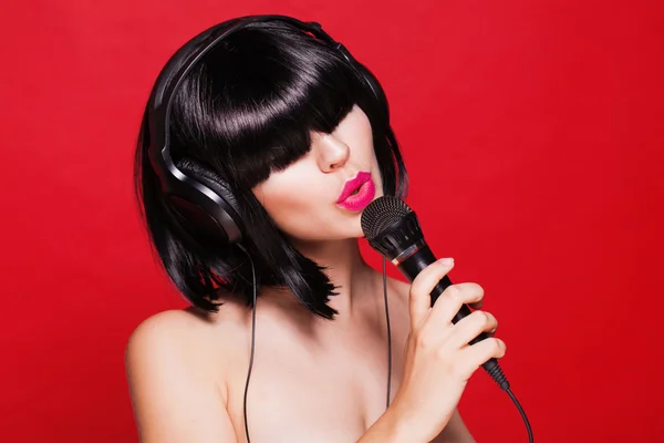 Frau hört Musik über Kopfhörer und genießt einen Gesang. Nahaufnahme Porträt eines schönen Mädchens mit rosa Lippen. Karaoke — Stockfoto