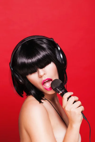 Woman listening to music on headphones enjoying a singing. Closeup portrait of beautiful girl with pink lips. Karaoke — Stock Photo, Image