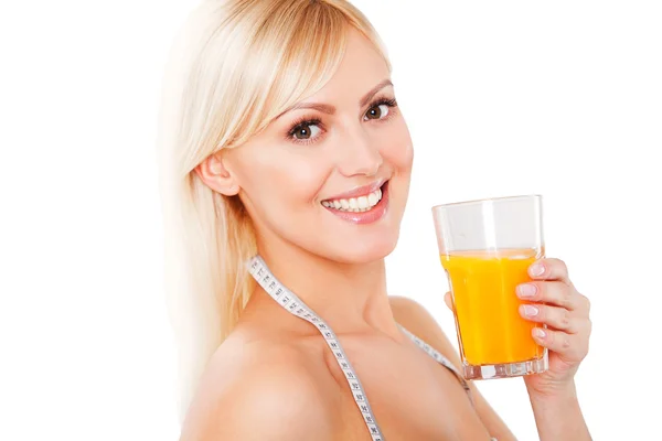 Blond woman with the measuring tape drinking orange juice — Stock Photo, Image