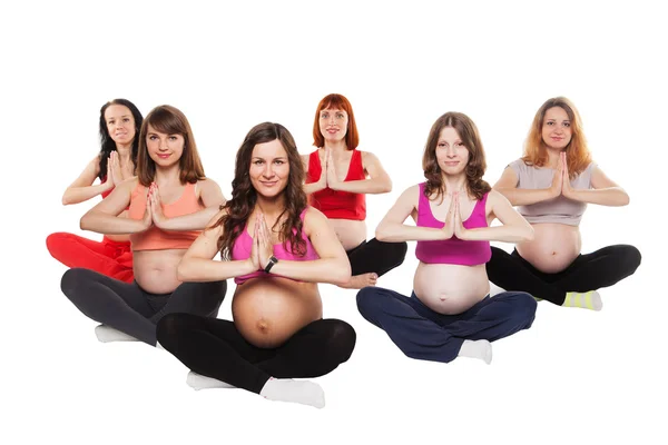 Grupo de mujeres embarazadas sonrientes sentadas en el suelo y practicando Yoga —  Fotos de Stock