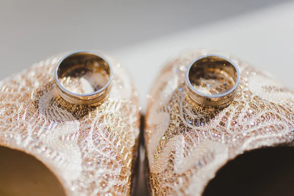 Alianças de casamento perto nos sapatos da noiva — Fotografia de Stock