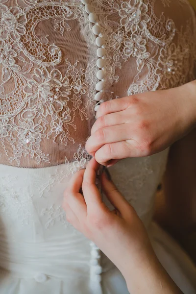 Bridesmaid's hands buttoning wedding dress — Stock Photo, Image