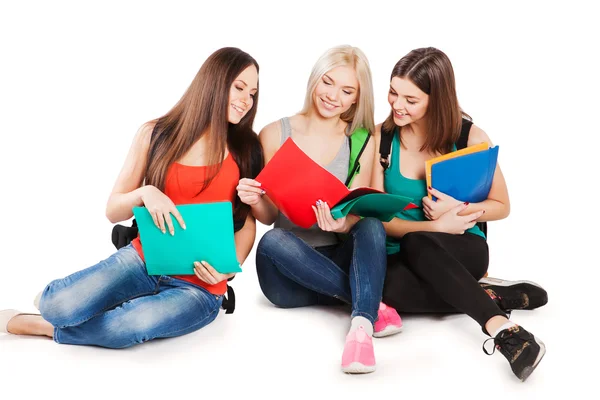 Three smiling college students sitting in a row against white background — Stock Photo, Image