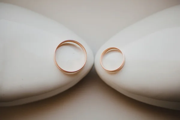 Two gold wedding rings laying on white bridal shoes — Stock Photo, Image