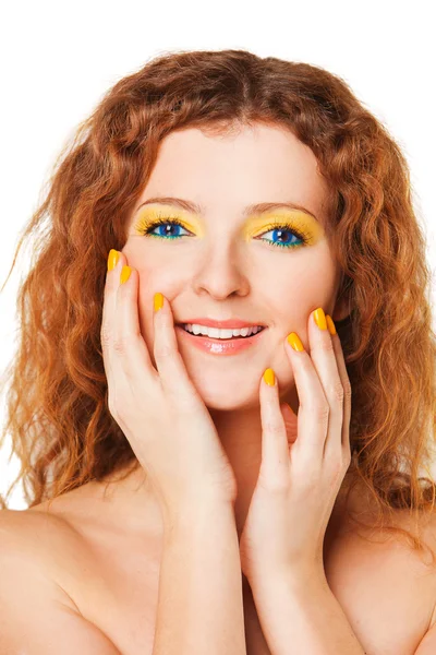Leende kvinna med rött lockigt hår och ljusa gula ögonskugga, naglar på den vita bakgrunden — Stockfoto