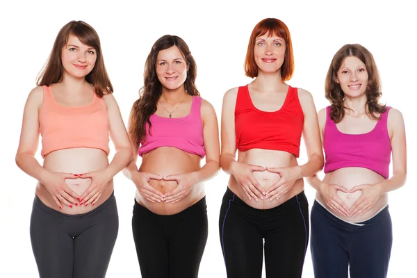 Grupo de mujeres embarazadas sonrientes sentadas en el suelo y tocándose el vientre —  Fotos de Stock