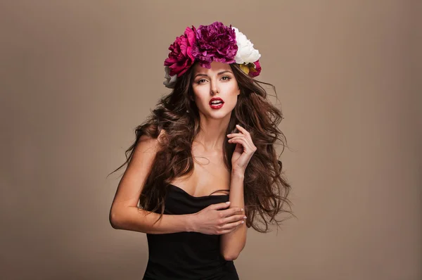 性感模特与柯尔头发和鲜艳的花朵，在她的头上 — 图库照片