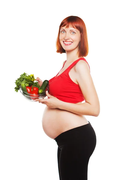 Młoda kobieta w ciąży gospodarstwa miski z sałatką na jasnym tle — Zdjęcie stockowe