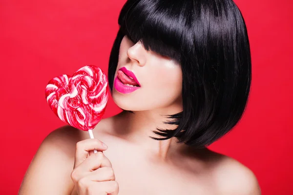 Closeup photo of a beautiful sexy pink lips with lollipop on red — Stock Photo, Image