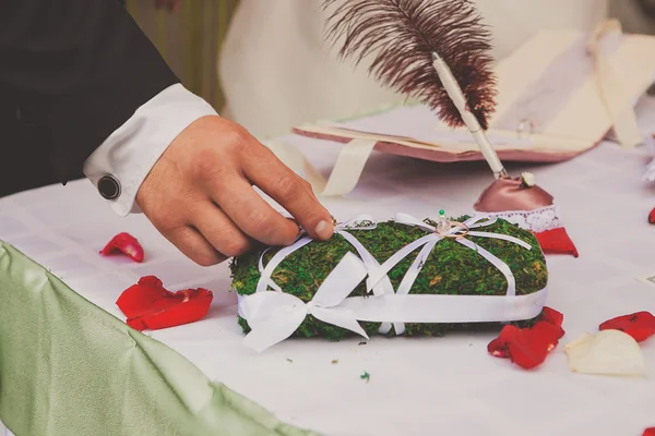 Groom taking wedding ring from the pillow — Stock Photo, Image