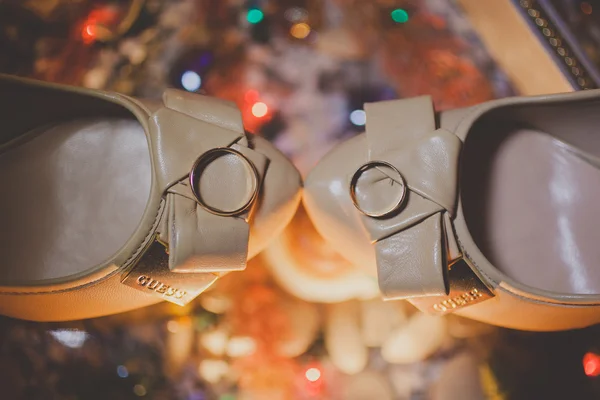 Two gold rings laying on wedding bridal shoes — Stock Photo, Image