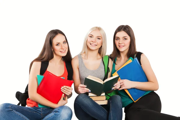 Três estudantes menina com livros sentados juntos em um fundo branco — Fotografia de Stock